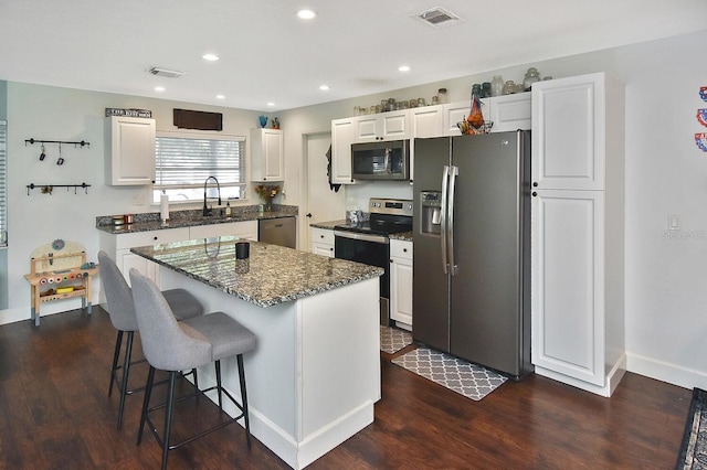 kitchen with white cabinetry, a center island, dark hardwood / wood-style floors, and appliances with stainless steel finishes