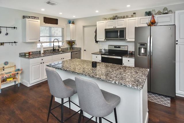 kitchen featuring white cabinets, a center island, dark hardwood / wood-style flooring, and stainless steel appliances