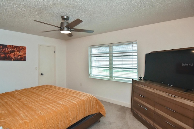 carpeted bedroom featuring ceiling fan and a textured ceiling