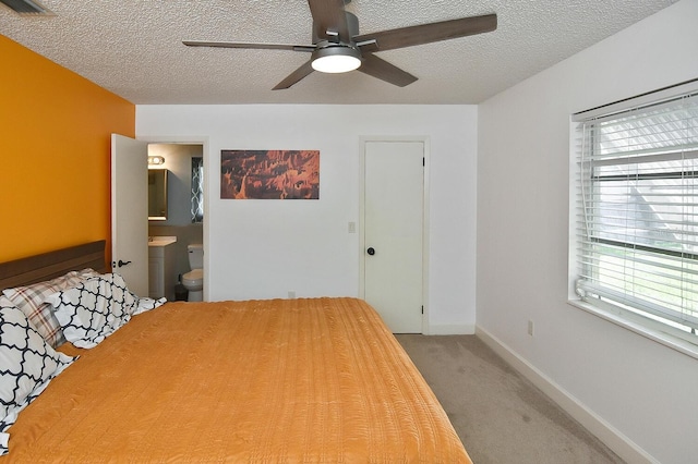 carpeted bedroom featuring a textured ceiling, ensuite bath, and ceiling fan