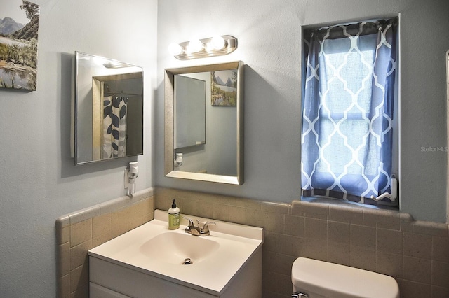 bathroom featuring vanity, toilet, and tile walls