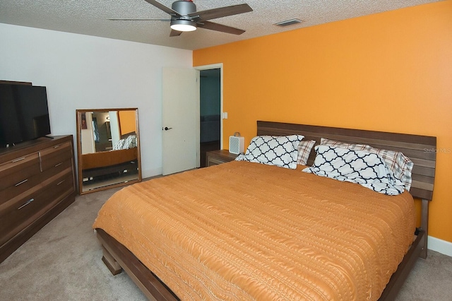 carpeted bedroom featuring ceiling fan and a textured ceiling