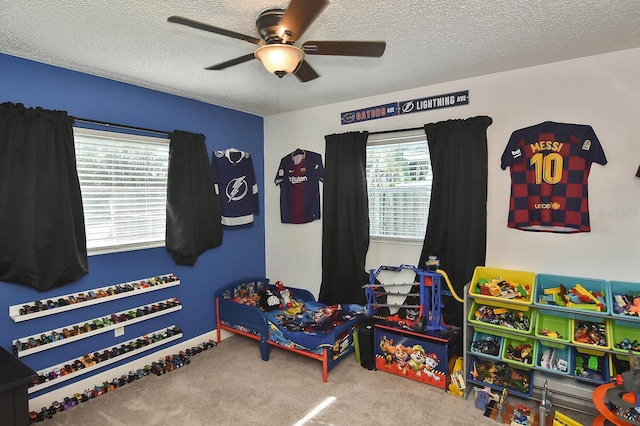 recreation room featuring carpet flooring, a textured ceiling, and ceiling fan