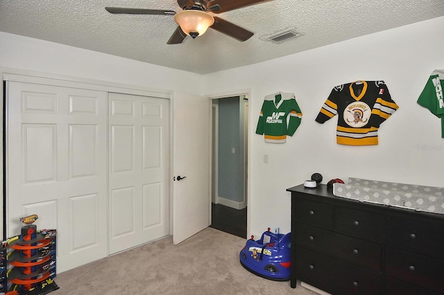 bedroom with ceiling fan, a closet, light carpet, and a textured ceiling