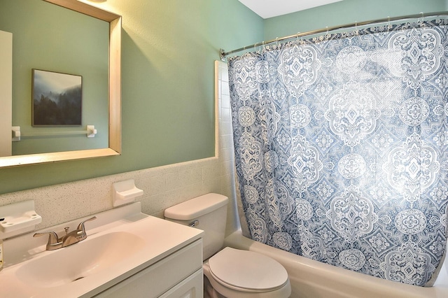 full bathroom with shower / bath combo, vanity, toilet, and tile walls