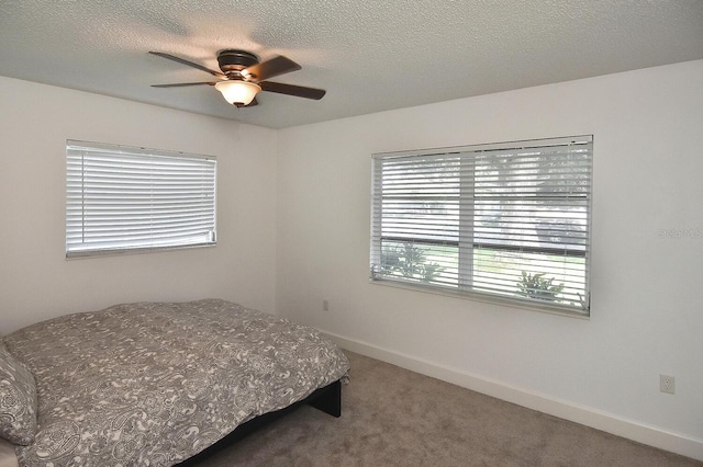 bedroom featuring carpet flooring, ceiling fan, and a textured ceiling