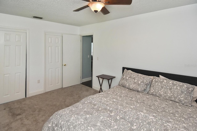 bedroom with ceiling fan, carpet, and a textured ceiling