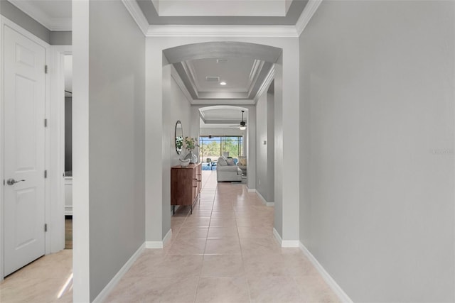 hall with light tile patterned flooring, a raised ceiling, and crown molding