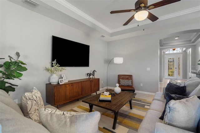 living room with ceiling fan, ornamental molding, and a tray ceiling