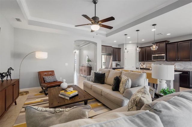 tiled living room featuring a tray ceiling, ceiling fan, and ornamental molding