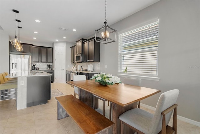 dining space with sink, light tile patterned floors, and a notable chandelier