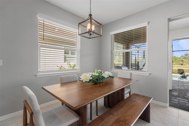 dining area with light tile patterned floors, a wealth of natural light, and an inviting chandelier