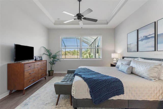 bedroom with ceiling fan, wood-type flooring, crown molding, and a tray ceiling