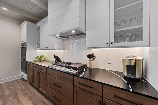 kitchen with stainless steel appliances, backsplash, light hardwood / wood-style floors, white cabinets, and custom exhaust hood