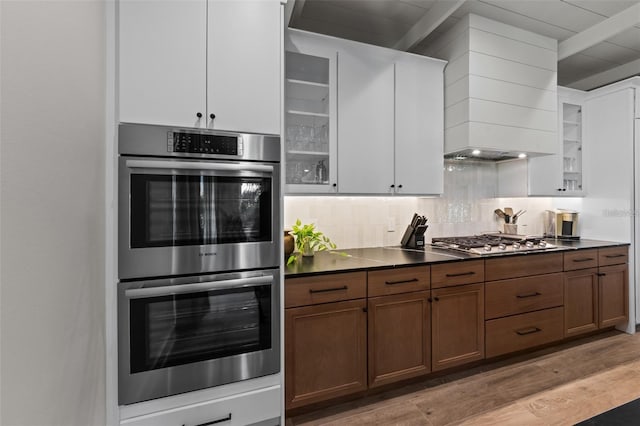 kitchen with decorative backsplash, light hardwood / wood-style flooring, white cabinets, and stainless steel appliances