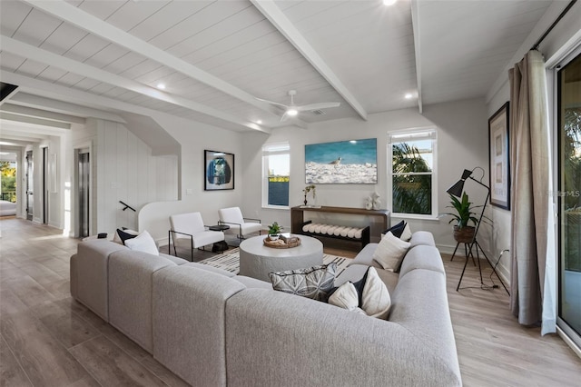 living room featuring beamed ceiling, light hardwood / wood-style flooring, and ceiling fan