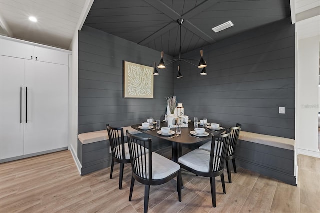 dining area with light wood-type flooring and wooden walls