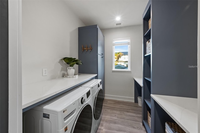 laundry room with washer and clothes dryer and light hardwood / wood-style flooring