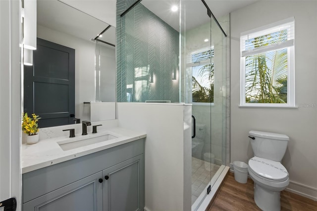 bathroom featuring hardwood / wood-style flooring, toilet, vanity, and walk in shower