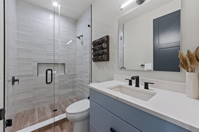 bathroom featuring vanity, toilet, and a shower with door