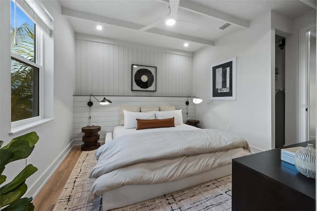 bedroom featuring beam ceiling, light wood-type flooring, and ceiling fan