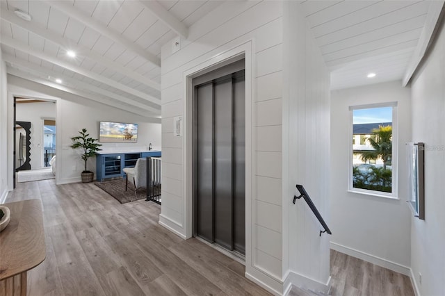 corridor featuring vaulted ceiling with beams, elevator, wooden ceiling, and light hardwood / wood-style floors