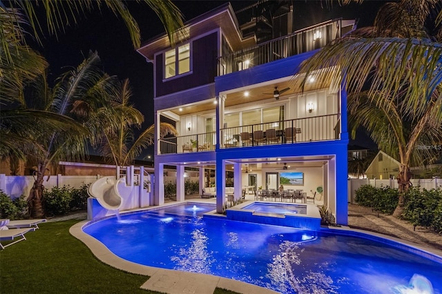 pool at night with ceiling fan, a patio area, an in ground hot tub, and a water slide