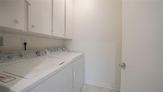 laundry room with cabinets, light tile patterned floors, and separate washer and dryer