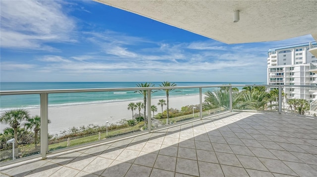 balcony featuring a view of the beach and a water view