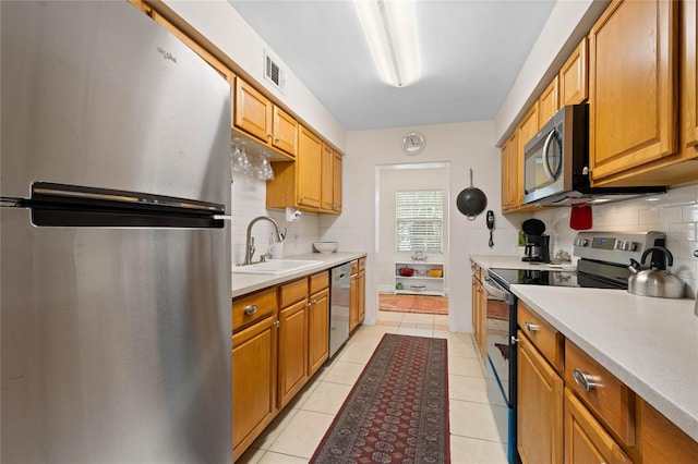 kitchen with light tile patterned flooring, backsplash, stainless steel appliances, and sink