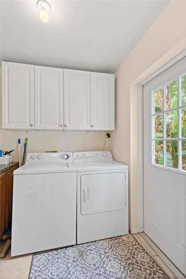 clothes washing area with cabinets and washer and dryer