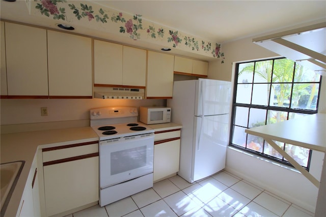 kitchen featuring white appliances, sink, light tile patterned floors, and cream cabinets