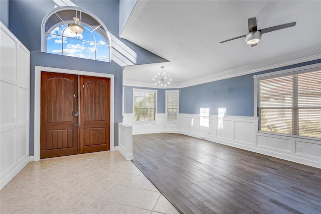 tiled entryway with ceiling fan with notable chandelier and ornamental molding