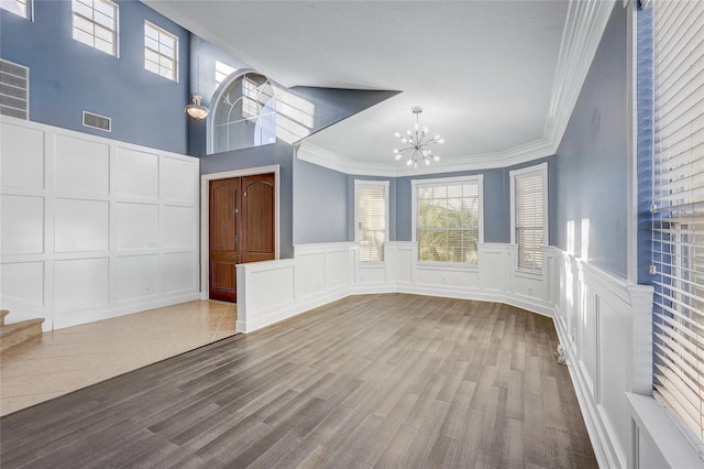 spare room with light hardwood / wood-style flooring, an inviting chandelier, and crown molding