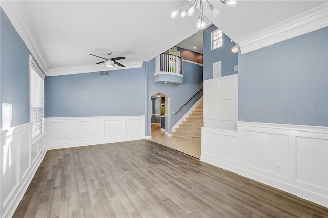 unfurnished room with ceiling fan with notable chandelier, hardwood / wood-style flooring, and ornamental molding