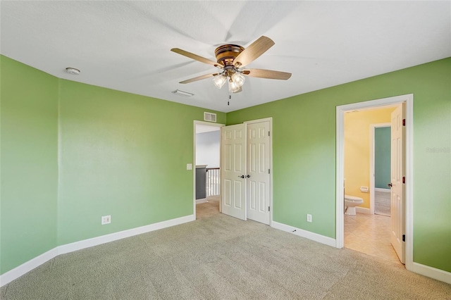 unfurnished bedroom featuring light colored carpet, ensuite bath, and ceiling fan