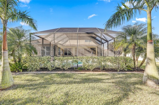 rear view of house with a lanai and a yard