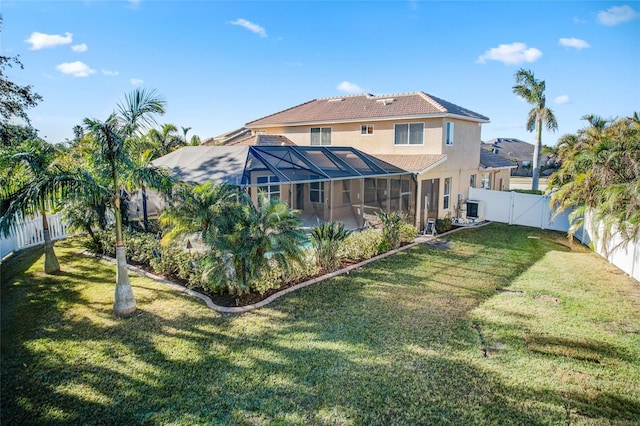 rear view of property with a lawn and glass enclosure