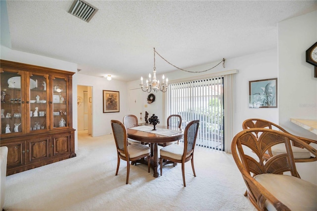 dining space with light colored carpet, a notable chandelier, and a textured ceiling