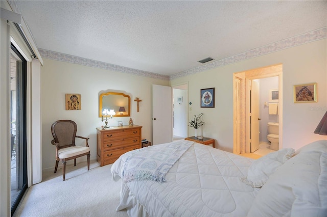 carpeted bedroom featuring ensuite bath and a textured ceiling