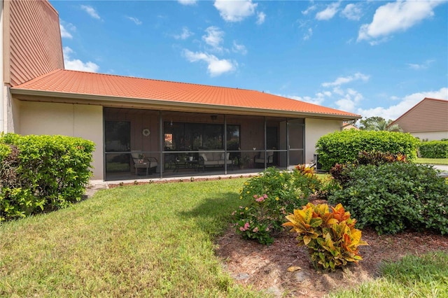 back of property featuring a yard and a sunroom