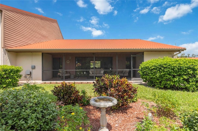 rear view of property with a yard, a sunroom, and a patio