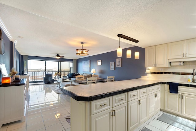 kitchen with crown molding, hanging light fixtures, ceiling fan, light tile patterned floors, and kitchen peninsula