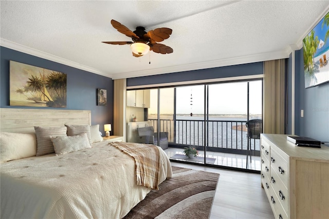 bedroom with access to exterior, ceiling fan, a textured ceiling, a water view, and ornamental molding