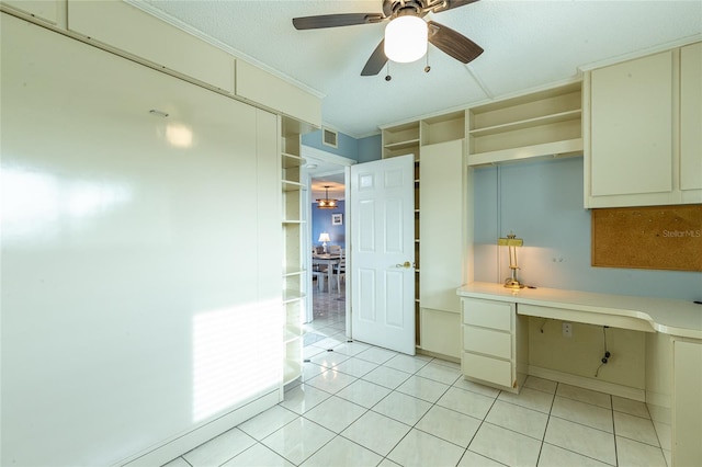 kitchen featuring cream cabinets, ceiling fan, built in desk, ornamental molding, and light tile patterned floors