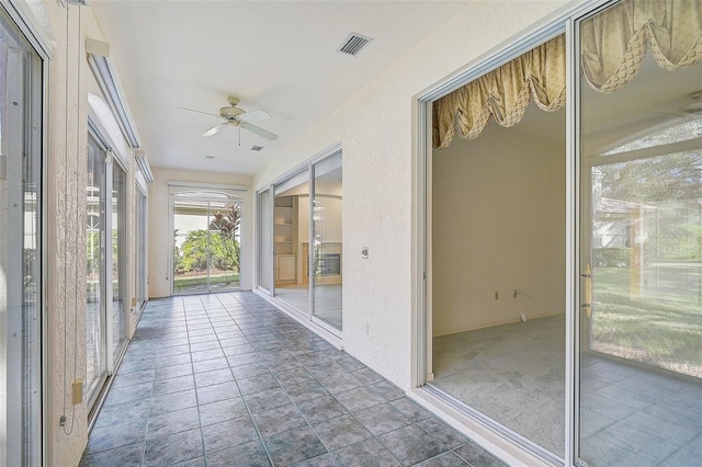 unfurnished sunroom featuring ceiling fan