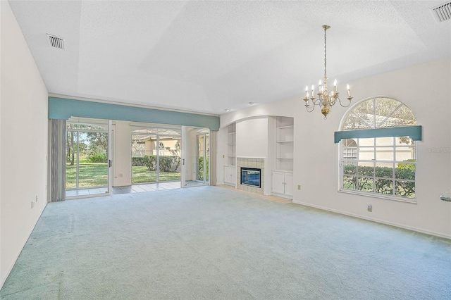 unfurnished living room with a raised ceiling, built in features, a textured ceiling, and a tile fireplace