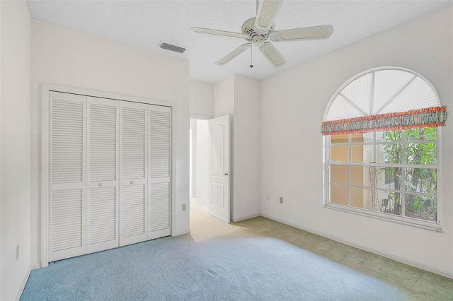 unfurnished bedroom with ceiling fan, a closet, and light colored carpet