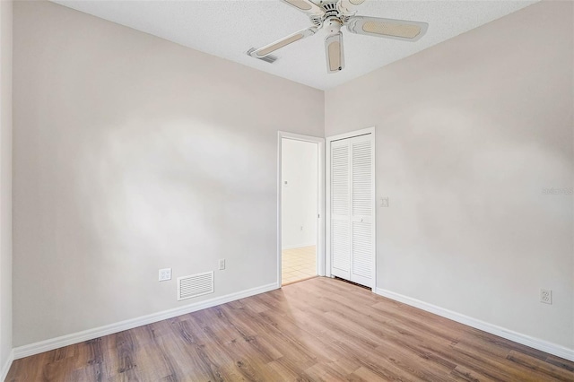 spare room featuring a textured ceiling, light hardwood / wood-style flooring, and ceiling fan