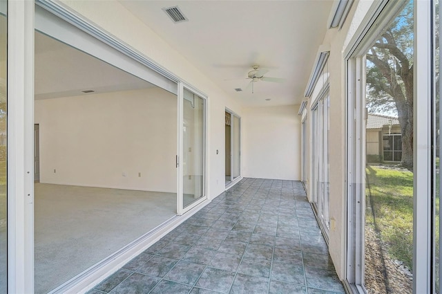 unfurnished sunroom featuring ceiling fan